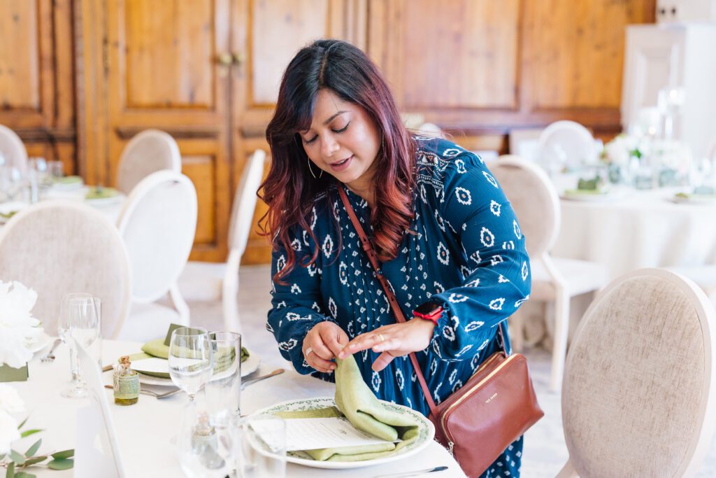 Luxury wedding coordinator Nalini Raman arranging napkins at Hedsor House for an Indian and Polish intercultural interfaith wedding